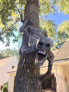 a statue of a lizard on a tree in front of a house