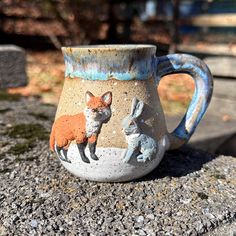 Sage & Slip pottery is all small batch, handmade artisan pottery by Victoria Pitt.  If you know me, you know I'm obsessed with all the cute woodland animals. This wintery snowy themed mug is perfect as a gift or for yourself as we move into the holiday season. The adorable fox and hare will keep you company while you sip your hot coffee or tea.  All elements were crafted by hand including a mug body thrown on the potter's wheel, a handle pulled by hand, hand sculpted elements and custom glazed.  This piece is dishwasher and microwave safe. Holds 10 oz.  All you have to do is not drop it, clank it hard against other objects, or give it to your dog to play with because like any piece of pottery, it can break if not handled with love and care. 😝👍 I ask that all sales are final but I'm also Slip Pottery, Artisan Pottery, The Fox, Small Batch, Woodland Animals, Handmade Artisan, Handmade Pottery, Hot Coffee, Stoneware