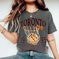 "Comfort Colors Toronto Basketball Shirt, Toronto Basketball Sweatshirt, Vintage Style Toronto Basketball shirt, Toronto Basketball fan Gift -Please check Color and Size Charts before placing the order. You can find them in the listing's photos (Depending on what device you are viewing this listing colors may vary slightly). -Returns and exchanges are accepted only if there are defects \"No Extra Costs\" We create custom t-shirts with great designs for everyone's liking. If you don't find the size or color you would like, please message us and we will be happy to  accommodate! Comfort Colors Toronto Basketball Shirt, Toronto Basketball Sweatshirt, Vintage Style Toronto Basketball shirt, Toronto Basketball fan Gift PRODUCT T-shirt Comfort Colors® 1717     Medium fabric (6.1 oz/yd² (206.8 g/ Sports Fan Tops With Sublimation Print For College, Sports Fan Graphic Print Crew Neck Top, Gray Team Spirit Tops With Text Print, Gray Team Spirit Top With Text Print, Gray Team Spirit Text Print Top, Gray Fan Apparel Tops For Sports Events, Trendy Sports Season Graphic Print Tops, Gray Crew Neck Top For Team Spirit, Gray Crew Neck Top For Sports Events