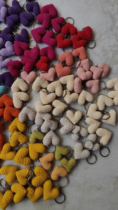 many different colored knitted objects are on the floor next to each other and one has a pair of scissors in it