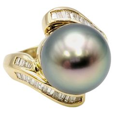 Ring size: 7.5 Sophisticated and elegant Tahitian pearl and diamond statement ring. The incredible, round peacock colored 13 mm pearl sits high at the center, demanding the viewers attention. Gently wrapping the base of the pearl in a modern bypass design are sparkling natural baguette shaped diamonds set in warm 18 karat yellow gold. This ring makes a bold and beautiful statement, truly decorating the finger. Ring size: 7.5 Metal: 18 Karat Yellow Gold Weight: 11.0 grams Tahitian Pearl diameter: Fine Jewelry Tahitian Pearl Ring With Diamond Accents, Luxury Tahitian Pearl Jewelry With Diamond Accents, Luxury Black Tahitian Pearl Ring, Luxury Multi-stone Pearl Ring Fine Jewelry, Luxury Tahitian Pearl Ring, Round Shape, Statement Rings Diamond, Peacock Color, Gold Cocktail Ring, Gold Cocktail