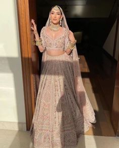 a woman in a bridal outfit standing by a door with her hands out to the side