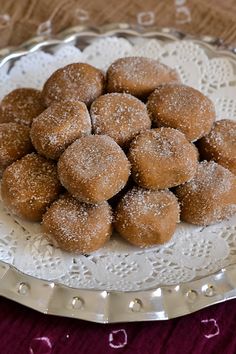 a plate full of sugared donuts on a doily