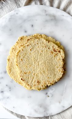 two tortillas sitting on top of a white marble plate next to a napkin