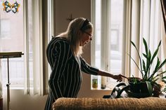 a woman is holding a potted plant in her living room