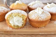 several cupcakes with icing and powdered sugar on a cutting board next to a measuring spoon