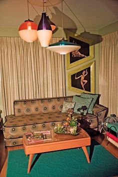 a living room filled with furniture and hanging lights above the couch, coffee table and rug