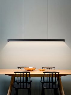 two bowls sit on top of a wooden table in front of a suspended light fixture