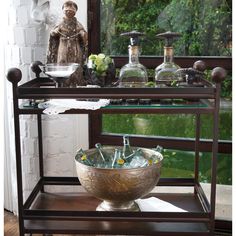 a metal shelf with bottles on it and a glass bowl sitting on top of it