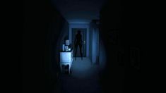 a dark hallway with a person standing at the door and light on in front of him