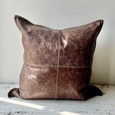 a brown leather pillow sitting on top of a white table