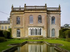 an old house with a pond in front of it