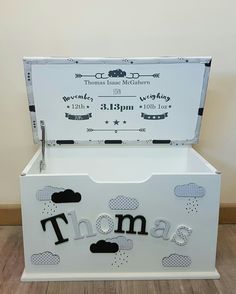 a white trunk with the word thomas written in black on it and clouds above it