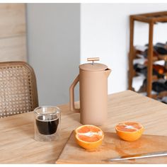 an orange sitting on top of a wooden table next to a cup and saucer