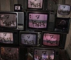 several tvs with graffiti on them stacked up