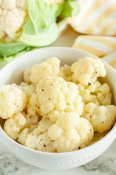 cauliflower and lettuce in a white bowl on a marble countertop