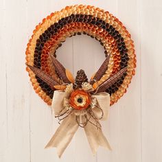 a wreath is hanging on the side of a white door with an orange and brown ribbon