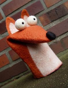 a close up of a stuffed animal on a brick wall