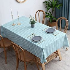 a blue table cloth with two plates on it and three candles in front of the table