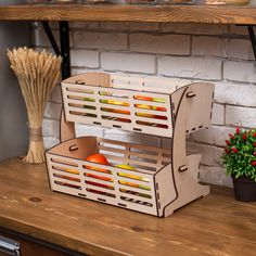 a wooden crate with fruit in it sitting on a table next to a potted plant