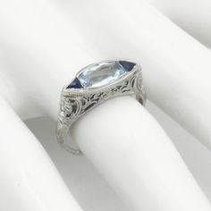 Beautiful 18K white gold filigree ring, with an aquamarine in the center and two sapphires. Ring Size: 6.25 can easily be sized by your jeweler Top Measures: 1/4" Wide x 5/8" across Hallmark: 18K Weight: 2.5 grams Condition: Great Condition Three Stone Sapphire Ring In Platinum For Formal Occasions, Formal Three Stone Sapphire Ring In Platinum, Formal Three-stone Sapphire Ring In Platinum, Formal Three Stone Sapphire Platinum Ring, Platinum Topaz Gemstone Ring For Wedding, Elegant Three Stone Birthstone Ring For Formal Occasions, Wedding Platinum Topaz Ring, Platinum Topaz Wedding Ring, Diamond Filigree Ring With Gemstone For Formal Events