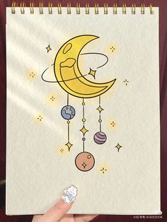 someone is holding up a drawing of the moon and planets on paper with gold trimmings