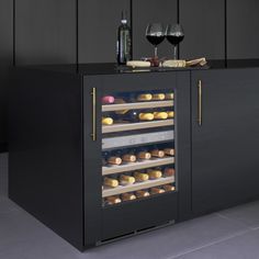 a black cabinet with two wine glasses on top and some food in the bottom shelf