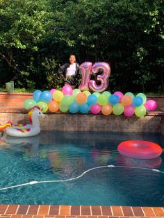 an inflatable number 13 balloon sitting on top of a pool next to a duck