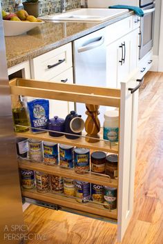 an open spice rack in the middle of a kitchen