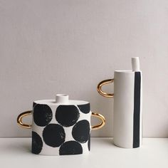 two black and white vases sitting next to each other on top of a table