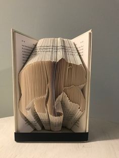 an open book with folded pages sitting on top of a table