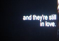 the words and they're still in love are projected on a dark background,