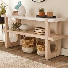 a wooden table with baskets under it and a round mirror on the wall behind it