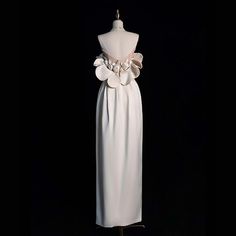 a white dress on a mannequin with flower detail at the waist and back