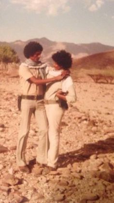 two people standing on rocks in the desert