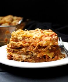 a white plate topped with lasagna casserole next to a serving dish