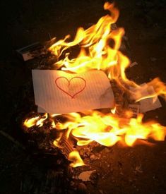 a piece of paper with a heart drawn on it sitting in the middle of fire