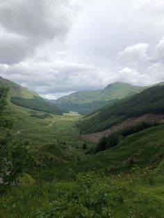 the valley is surrounded by green hills and trees