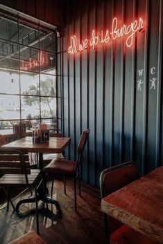 an empty restaurant with tables and chairs in front of a neon sign that reads, all we do is burgers