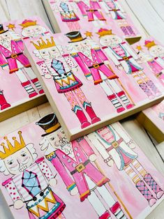 four pink and yellow wooden paintings with nutcrackers on them