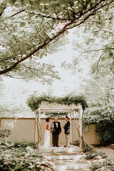 the bride and groom are getting married under an arbor