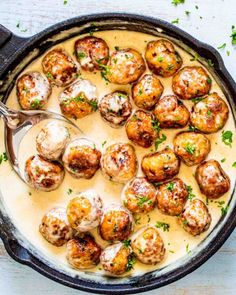 a skillet filled with meatballs covered in gravy and garnished with parsley