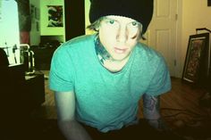 a young man wearing a black beanie sitting on top of a wooden floor next to a door