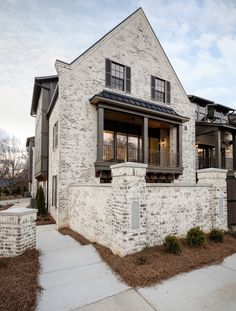 a white brick house with black shutters and balconies on the second story