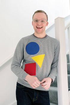 a man standing in front of some stairs wearing a sweater with geometric shapes on it