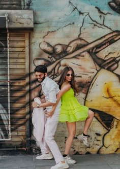 a man and woman standing in front of a graffiti wall