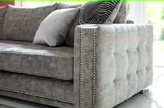 a gray couch with pillows on it in front of a window