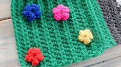 three crocheted potholders with flowers on them sitting next to each other in front of a wooden table