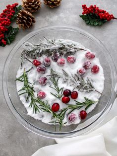 a glass plate topped with cranberries and pine cones covered in powdered sugar