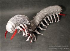 a paper sculpture of a bird with red feathers and long beaks on it's back